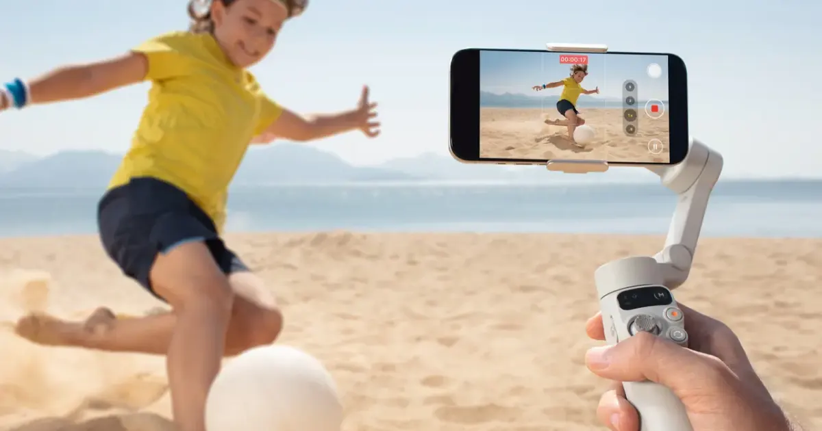 A creator holds the light-gray DJI Osmo Mobile 7 while filming outdoors